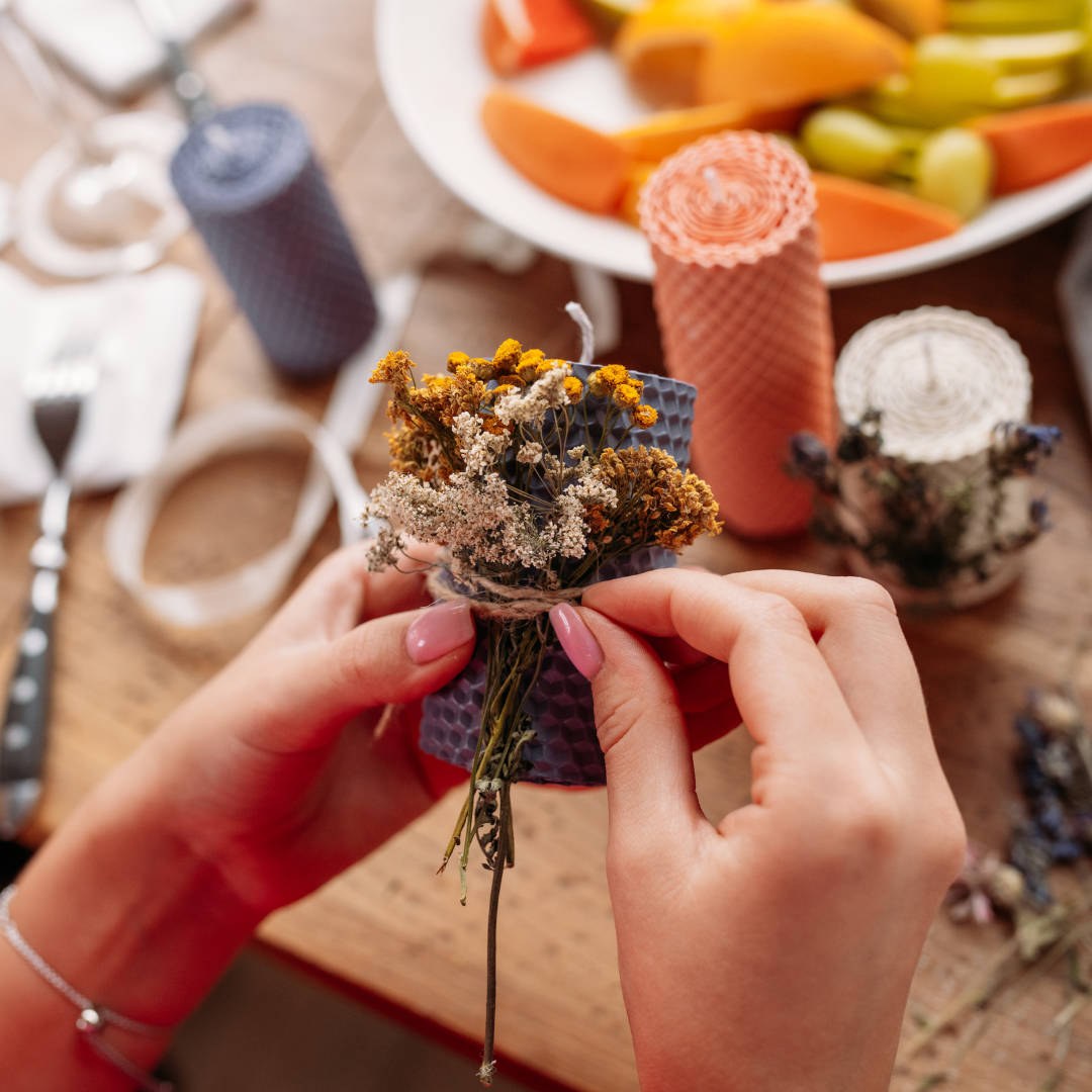 A women hands tying dried flowers to a candle