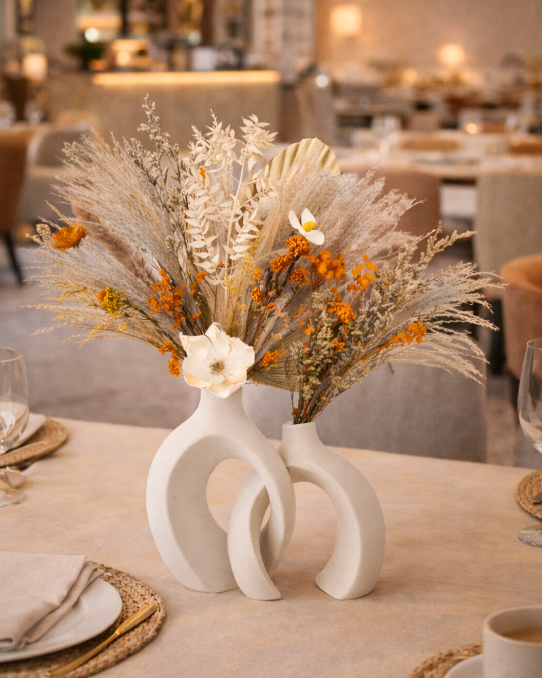 Decorative dried floral arrangement in a white vase on a table in a restaurant setting | Fleur Reverie
