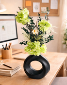 Decorative black vase with green preserved flowers on a desk in an office setting | Fleur Reverie