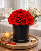 Black cylindrical vase with red preserved roses on a wooden tray with candles and rose petals | Fleur Reverie | Austin TX