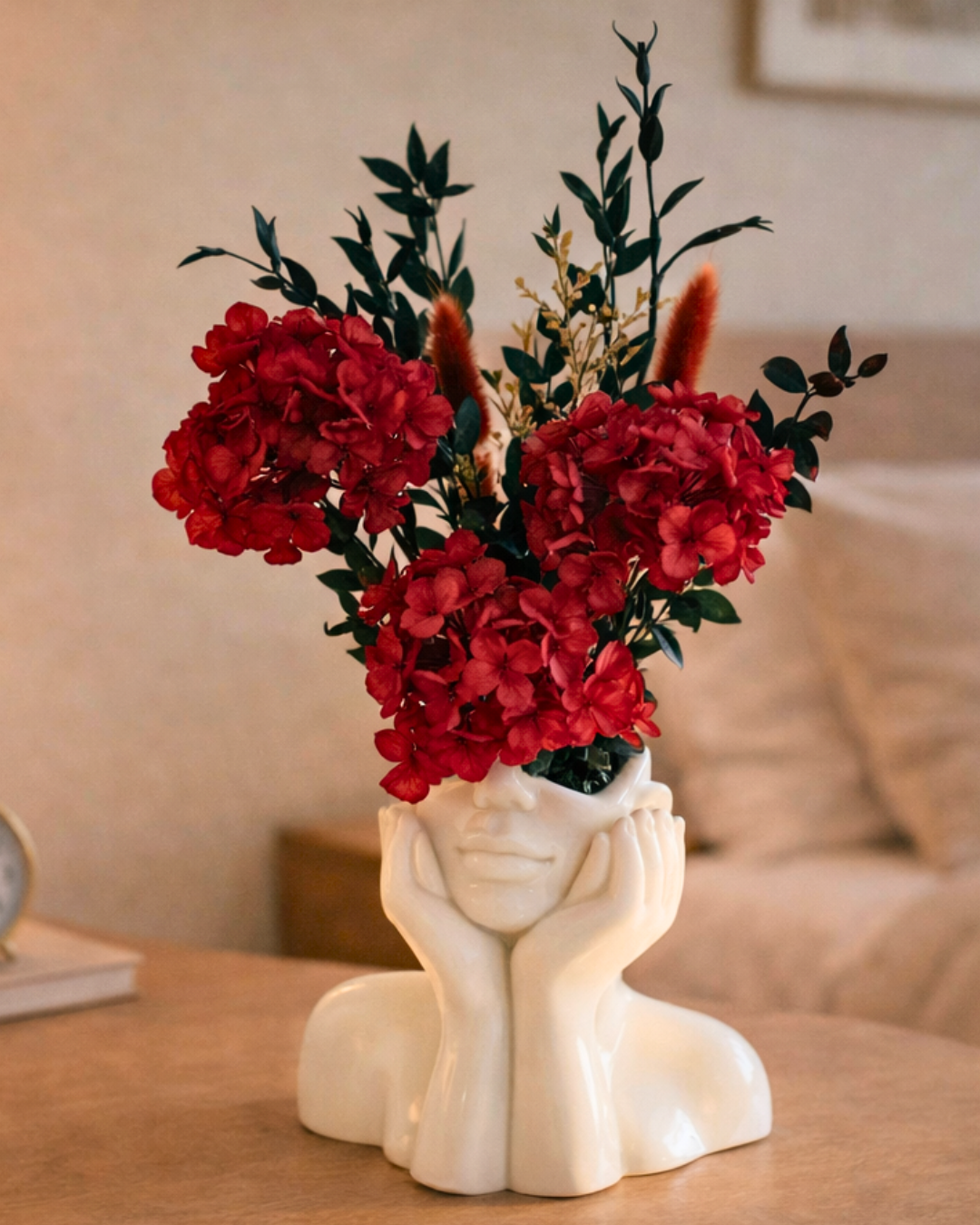 Decorative vase shaped like a face with red preserved flowers on a table