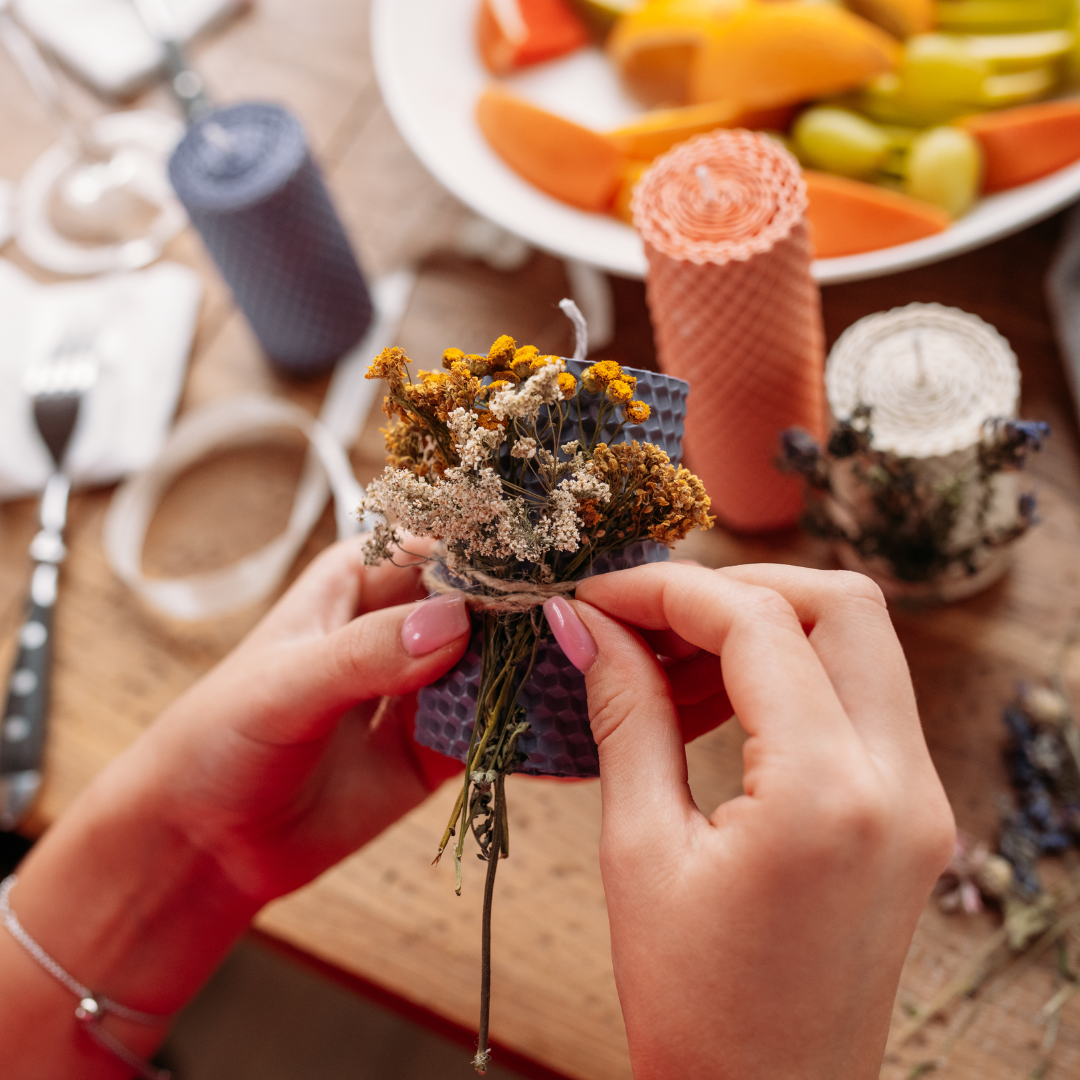 A women hands tying dried flowers to a candle 