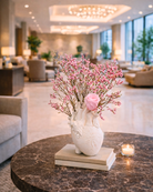 Decorative vase with pink dried flowers in a anatomical vase on a marble table in a stylish room.