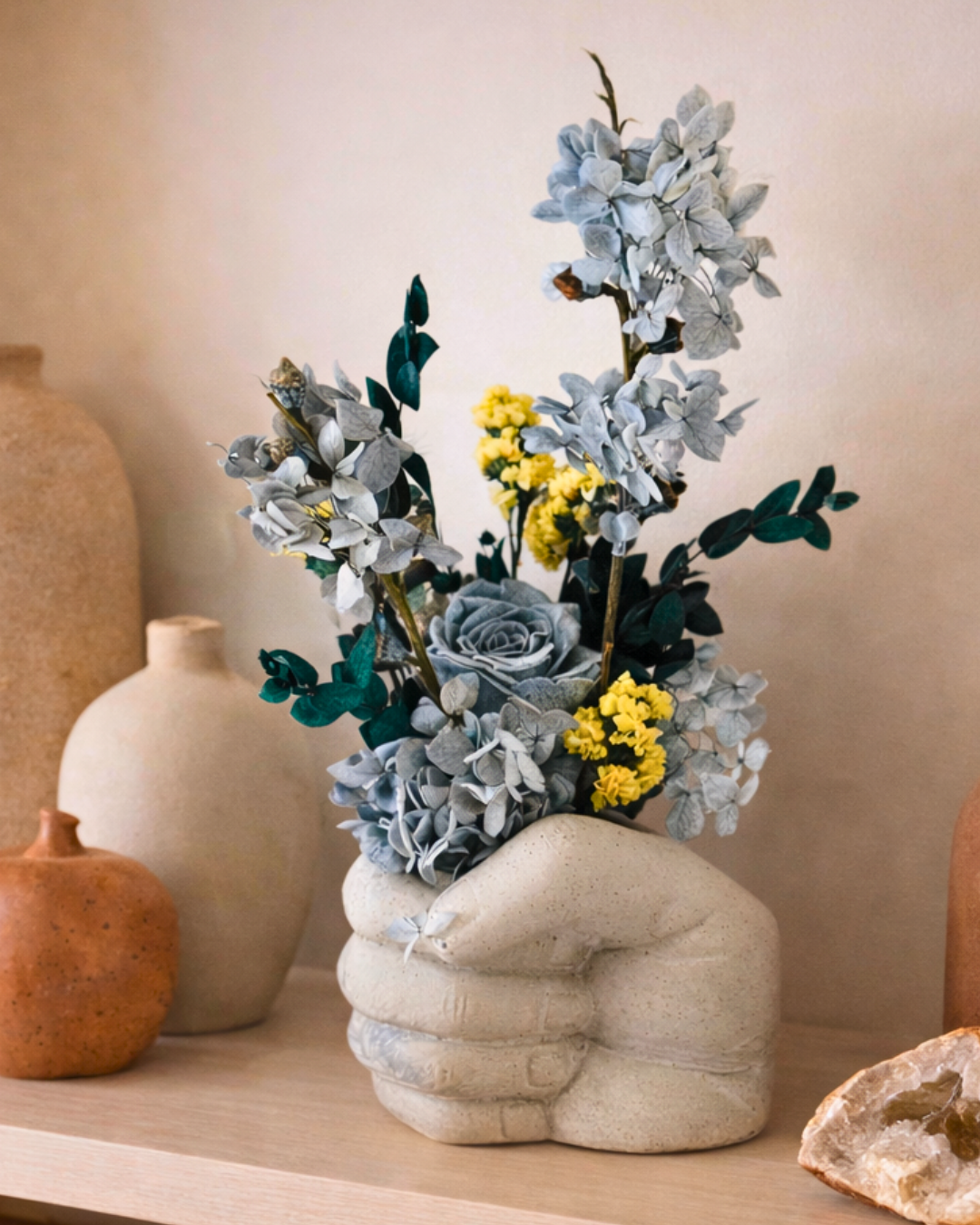 Decorative vase shaped like a hand holding preserved flowers on a shelf | Fleur Reverie