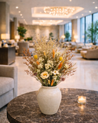 Decorative vase with preserved wild flowers on a marble table in a modern lobby setting